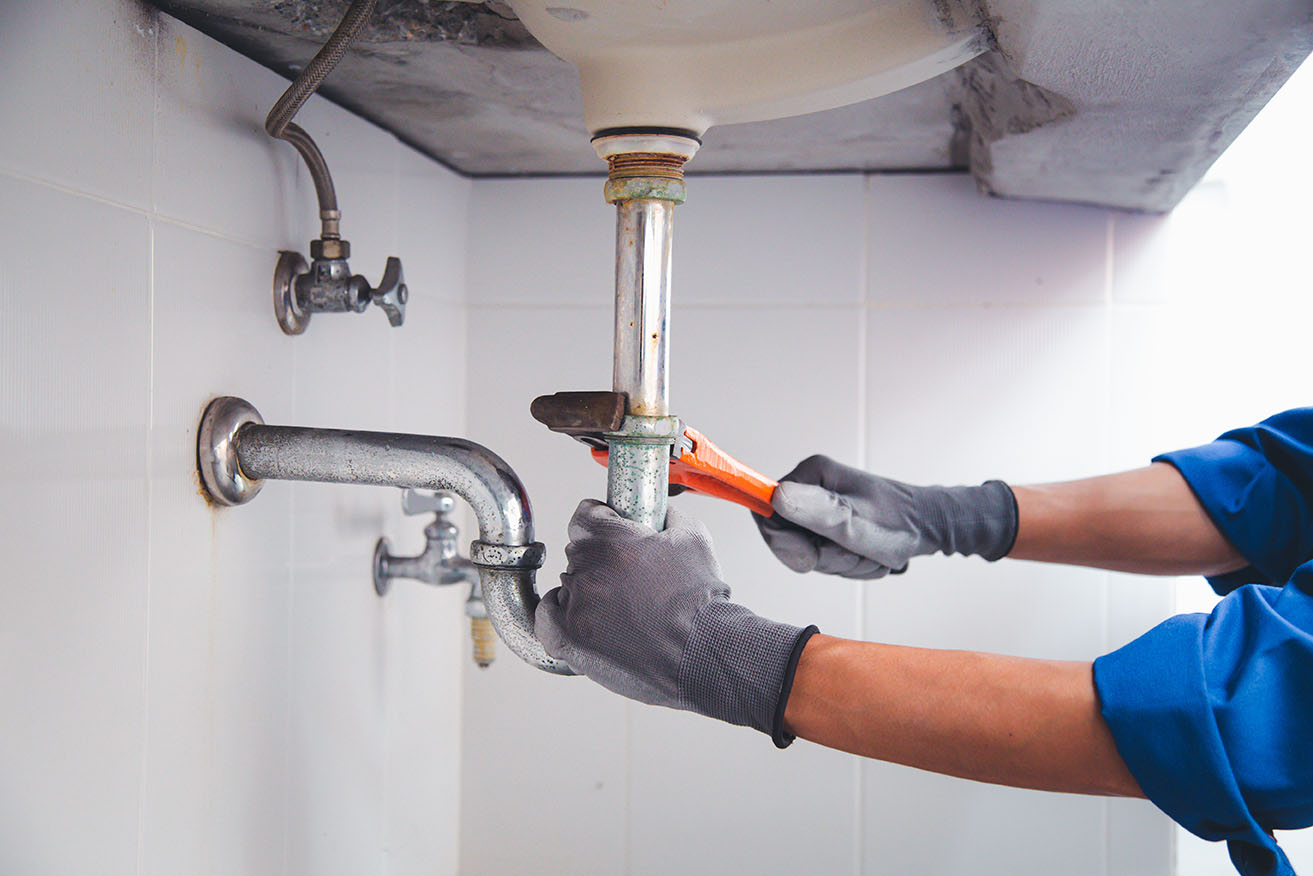 A commercial engineer's gloved hands working on pipework